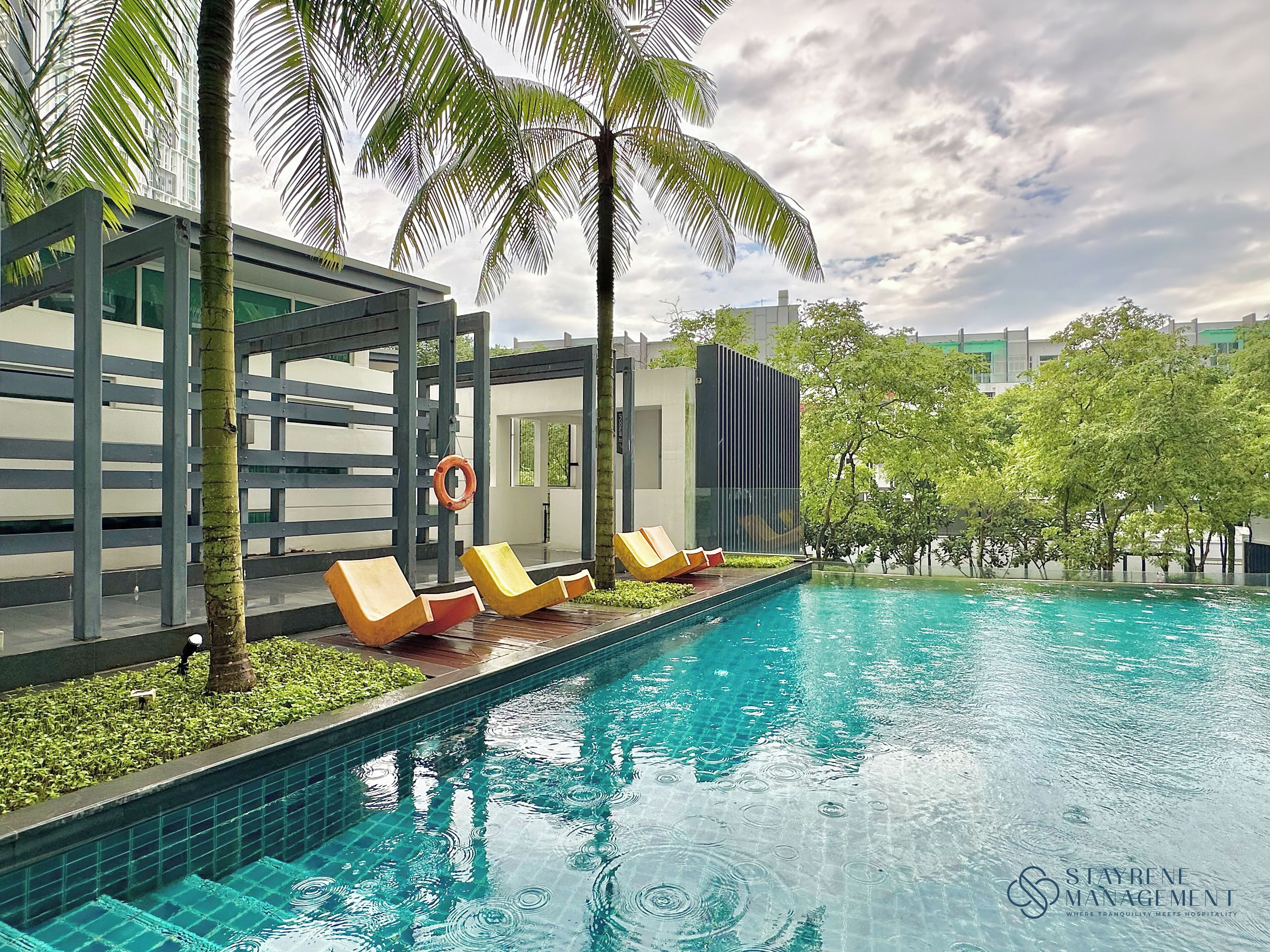 A swimming pool with lounge chairs and palm trees.