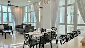 A modern dining area with a table set for four, surrounded by black chairs with intricate designs. - 1 Medini Residence Neo by Stayrene (Iskandar Puteri)