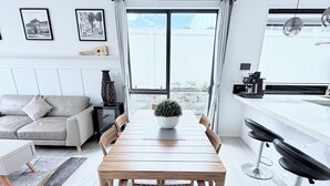 Un salon moderne comprenant une table à manger, un canapé et une grande fenêtre avec des rideaux.
