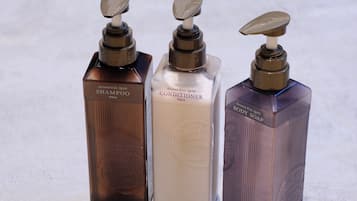 Three bottles of personal care products with pumps, labeled as shampoo, conditioner, and body soap.