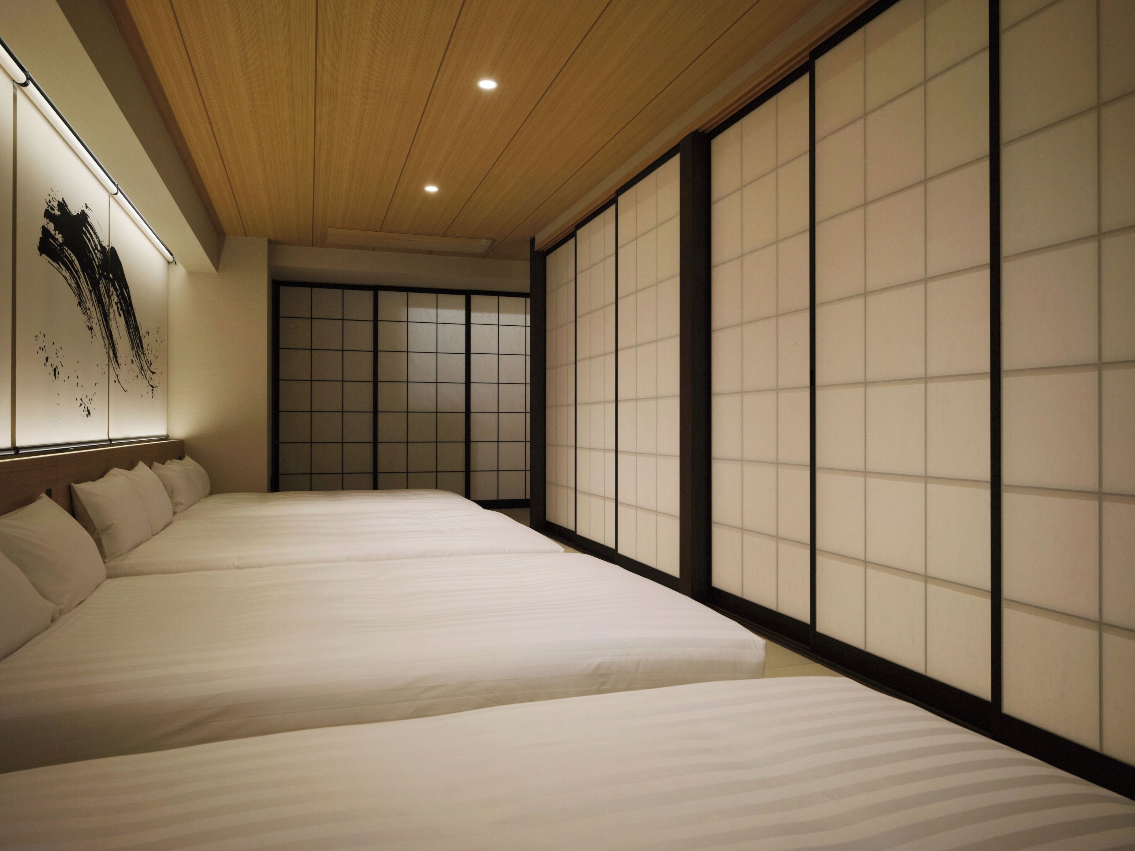 A traditional Japanese-style bedroom with tatami flooring, sliding doors, and a low wooden ceiling.