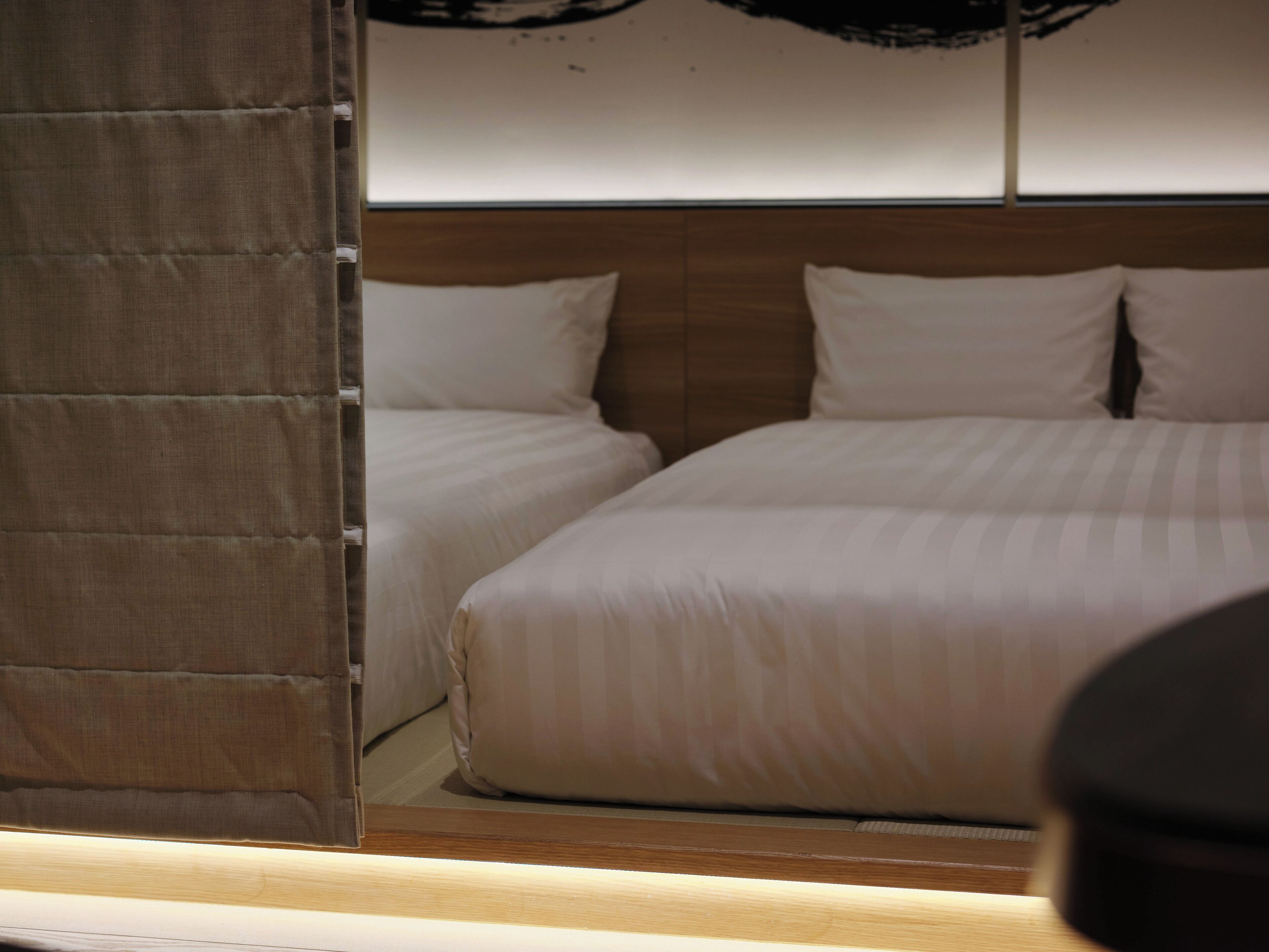 A hotel room with two beds, a wooden headboard, and a curtain.