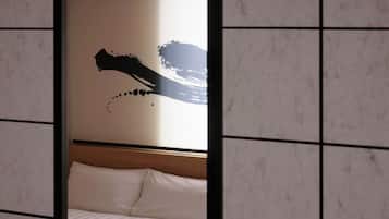Una habitación de hotel con una cama, cabecera y pared con diseño abstracto en negro.