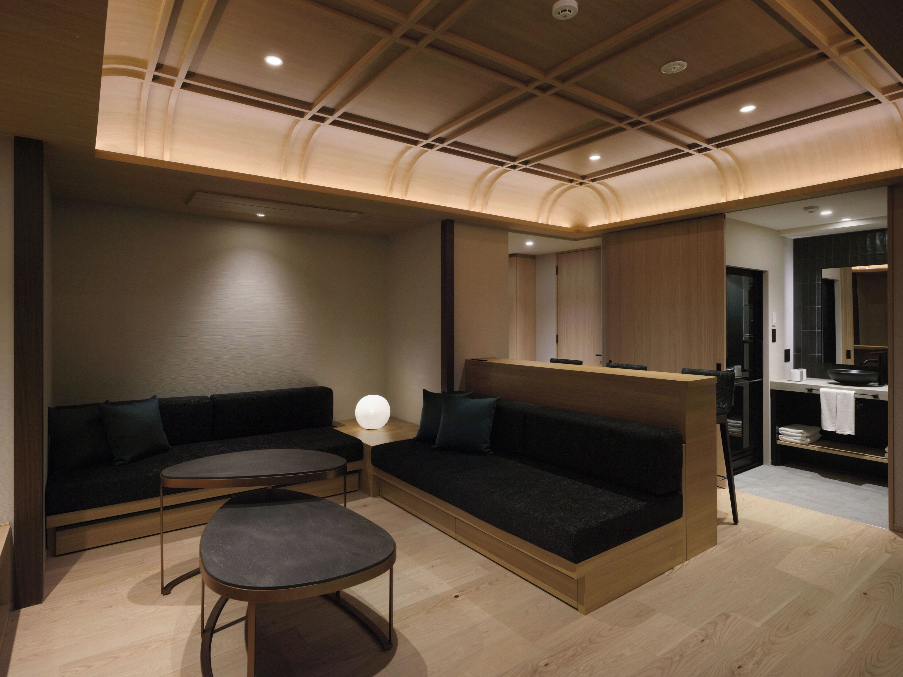 Ein modernes Interieur mit einer Couch, einem runden Tisch und einer Holzbalkendecke.