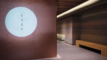 Ein modernes Interieur mit einer strukturierten Wand, einem runden Schild mit Buchstaben und einer hölzernen Bank.