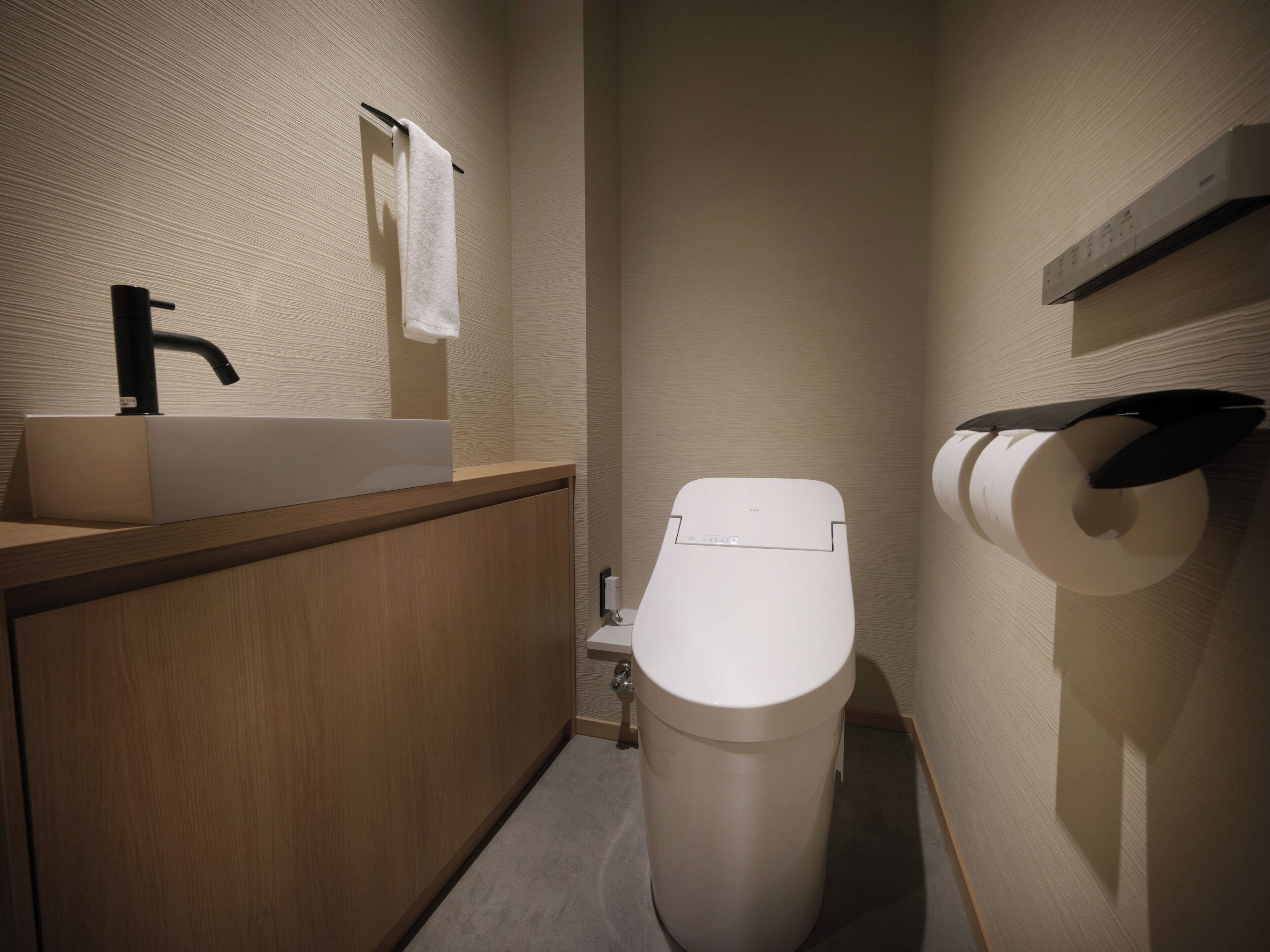 Une salle de bain moderne équipée d’un lavabo, de toilettes et d’un porte-serviettes.