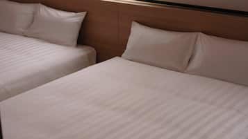 A hotel room with two beds, wooden headboard, and a window.