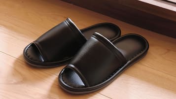 A pair of black slippers on a wooden floor.