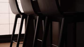 A row of dark-colored chairs with a simple design, positioned in front of a window with a grid pattern.
