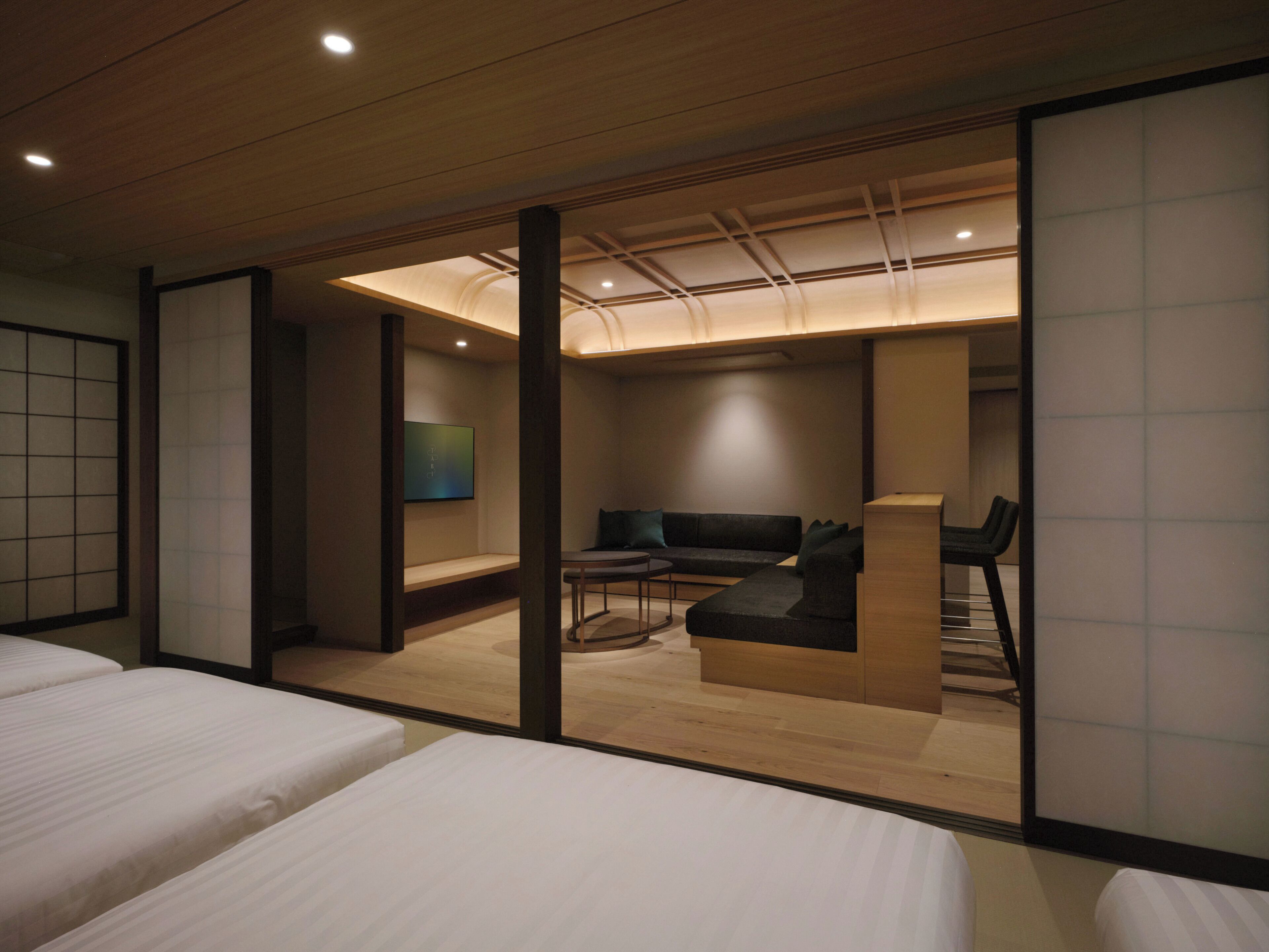 A hotel room with a wooden ceiling, a sofa, a small table, and a bed.