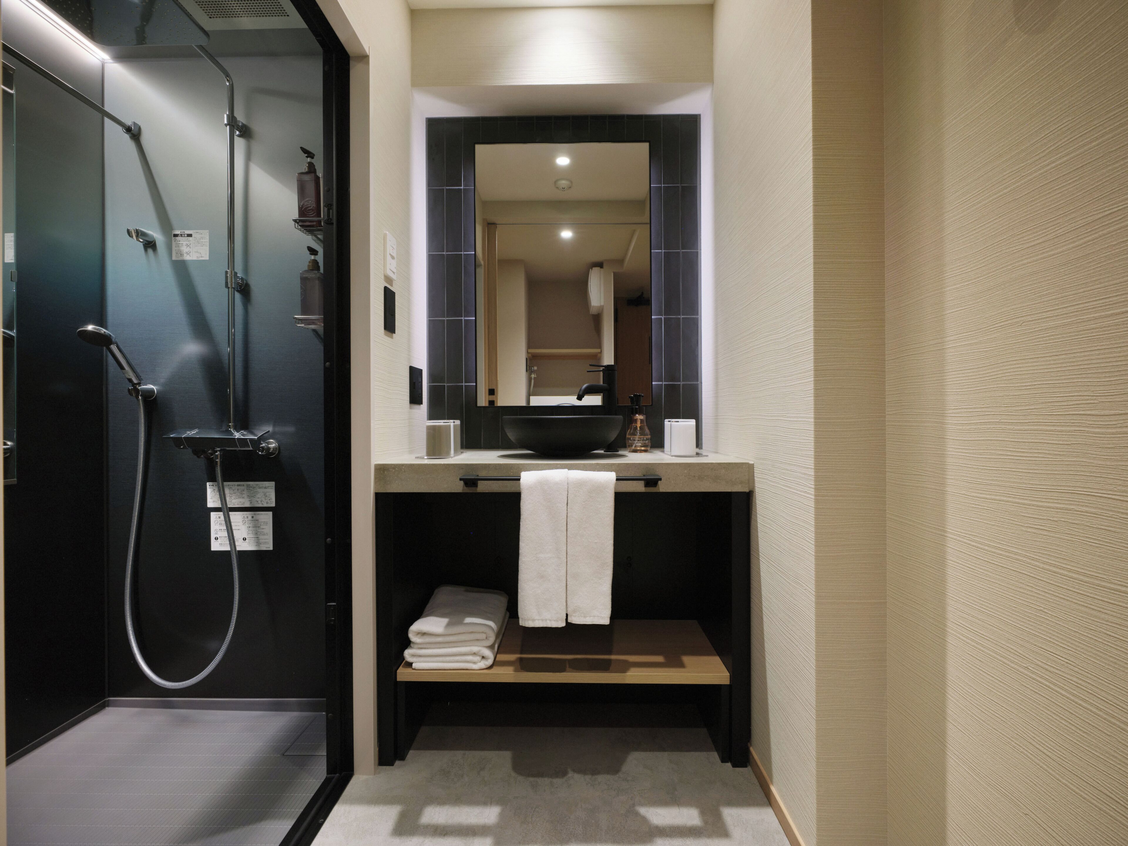 A modern bathroom with a black shower, a sink with a mirror above it, and a towel rack.