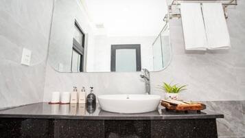 A bathroom with a large mirror, a white sink, and a vanity with toiletries.