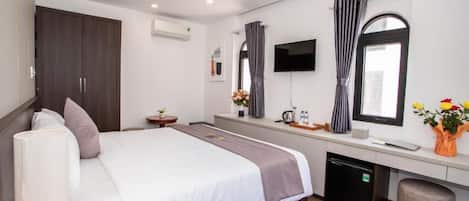 Una camera d'albergo moderna con un letto grande, una scrivania, una televisione e un armadio.