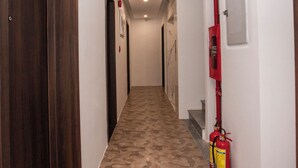 A hallway with wooden doors, a fire extinguisher, and a red emergency exit sign. - Nile Hotel Phu Yen  (Tuy Hoa)