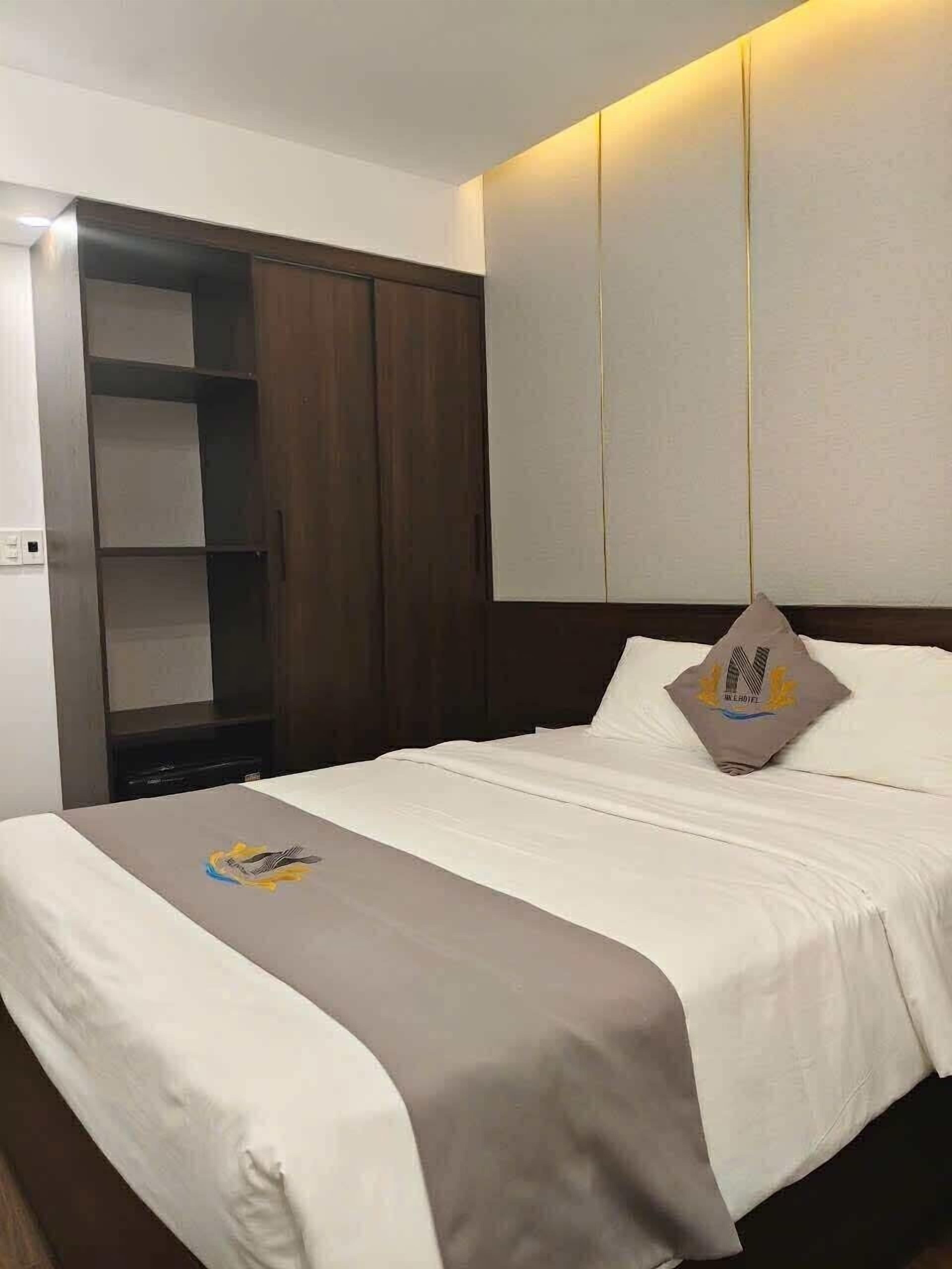 Una camera d'albergo con un letto, un armadio e una mensola a muro.