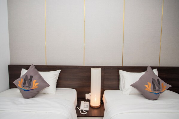 Habitación de hotel con dos camas, teléfono en la mesita de noche y una lámpara de noche.