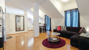 Ein modernes Wohnzimmer mit einer dunkelgrauen Couch, einem runden Couchtisch und einem Essbereich im Hintergrund.