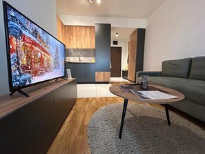 A modern living room with a flat-screen TV, a grey sofa, and a coffee table. - Cozy Skopje Apartment Modern Comforts Scenic Views (Skopje)