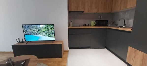 Et moderne køkken med lysegrå skabe, en træbordplade og en sort mikroovn.