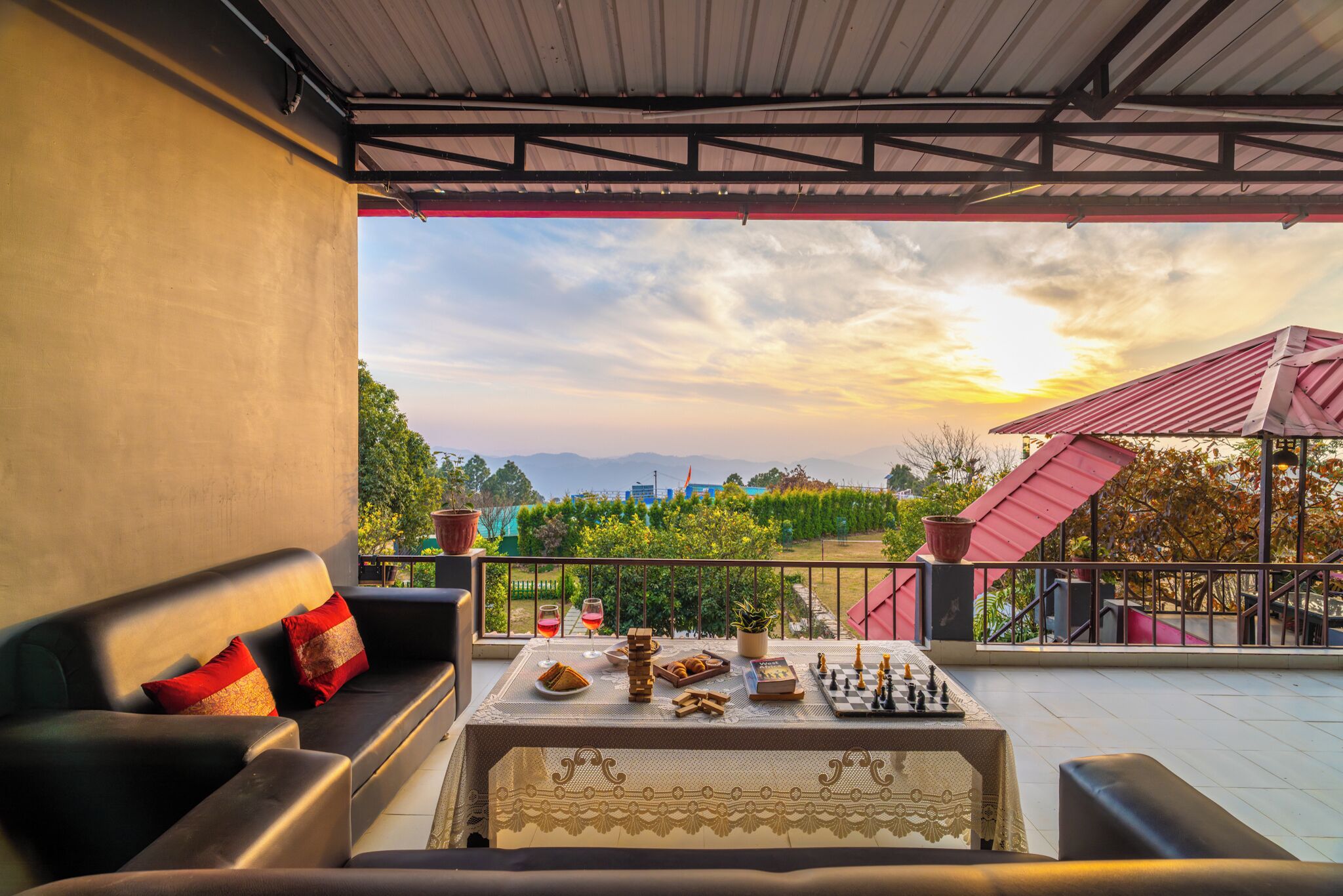 A terrace with a sofa, a table with chess and snacks, and a sunset view.