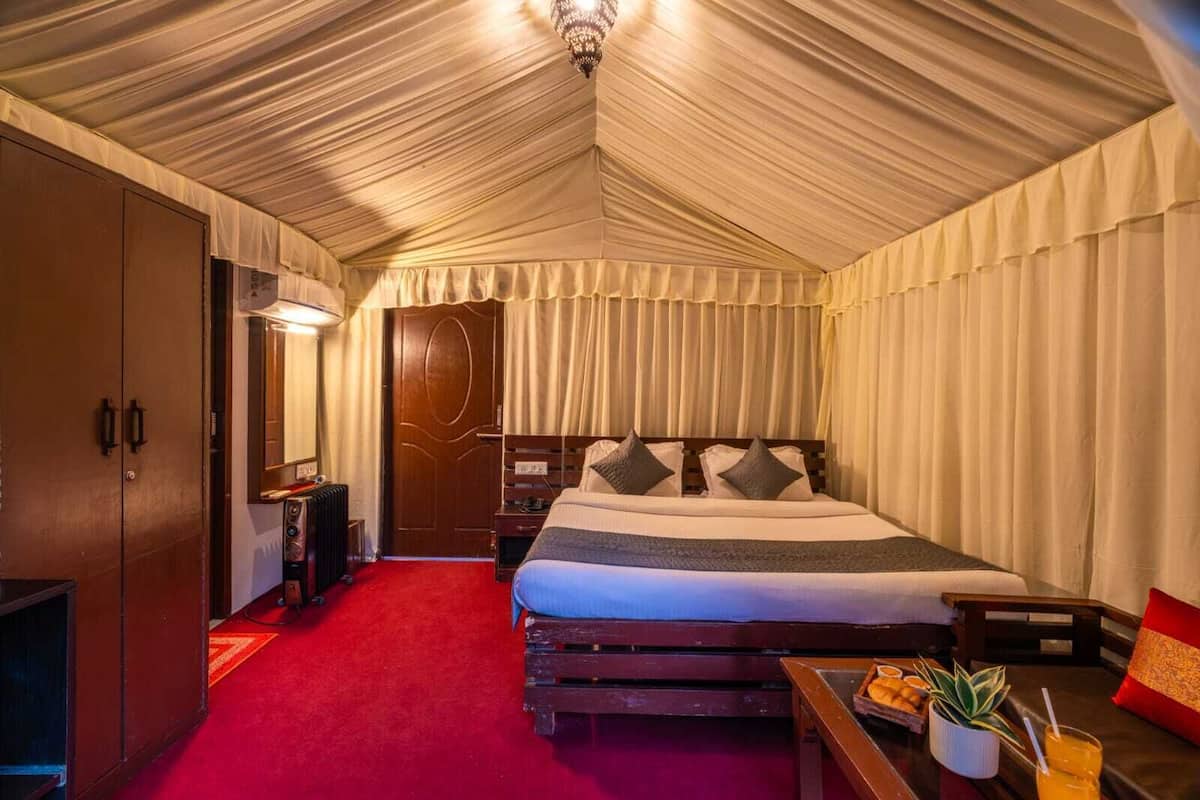 A room with a large bed, wooden wardrobe, and a red carpet.