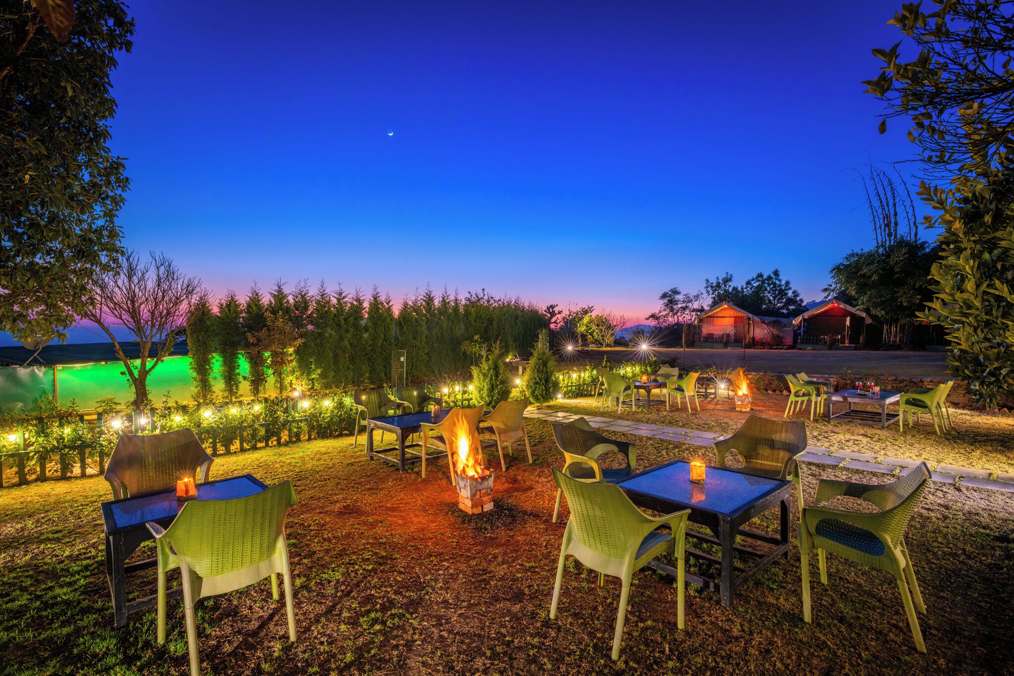 An outdoor seating area with tables and chairs, a fire pit, and a view of the sky.
