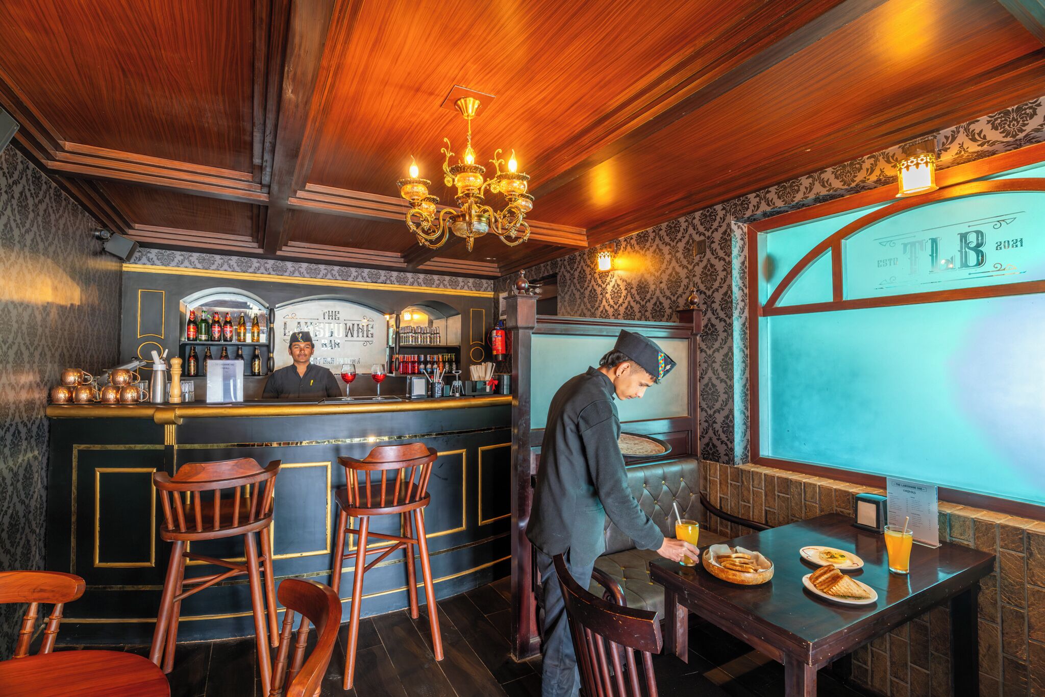 A bar area with wooden furniture, a bar counter, and a chandelier.