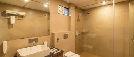 A modern bathroom with a large mirror, a sink, a toilet, and a glass-enclosed shower.