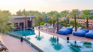 A rooftop pool area with lounge chairs and a small building, surrounded by palm trees. - Citygate 2 BR Pool View P503-4 (Kamala)