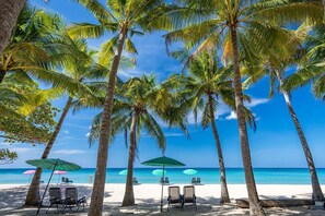A beach with palm trees, beach chairs, and umbrellas. - Citygate 2 BR Pool View P503-4 (Kamala)
