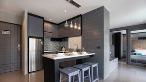 A modern kitchen with a central island, bar stools, and a built-in refrigerator. - Citygate 2 BR Pool View P503-4 (Kamala)