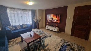 Ein Wohnzimmer mit einer Couch, einem Couchtisch, einem Fernseher und einem Kamin.