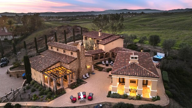 Une grande maison à plusieurs étages, dotée d’un patio, d’un espace salon extérieur et d’un jacuzzi.