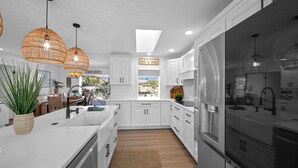 Una cocina moderna con armarios blancos, una isla grande e iluminación colgante.