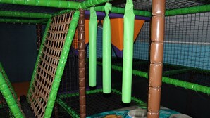 A play area with a netted enclosure, a climbing structure, and a table with a cartoon design. - Minicamping De Lindenhoeve - Chalet Alpaca (Nistelrode)