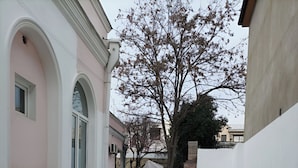A narrow alleyway with a brick floor, white walls, and a tree in the background. - Paradise Garden Tbilisi (Tbilisi)