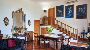 Un salon spacieux comprenant un coin repas, un escalier et un grand miroir.