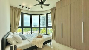 A modern bedroom with a curved bed, a ceiling fan, large windows, and a wardrobe. - Macrolink Medini Legoland by Stayrene (Iskandar Puteri)