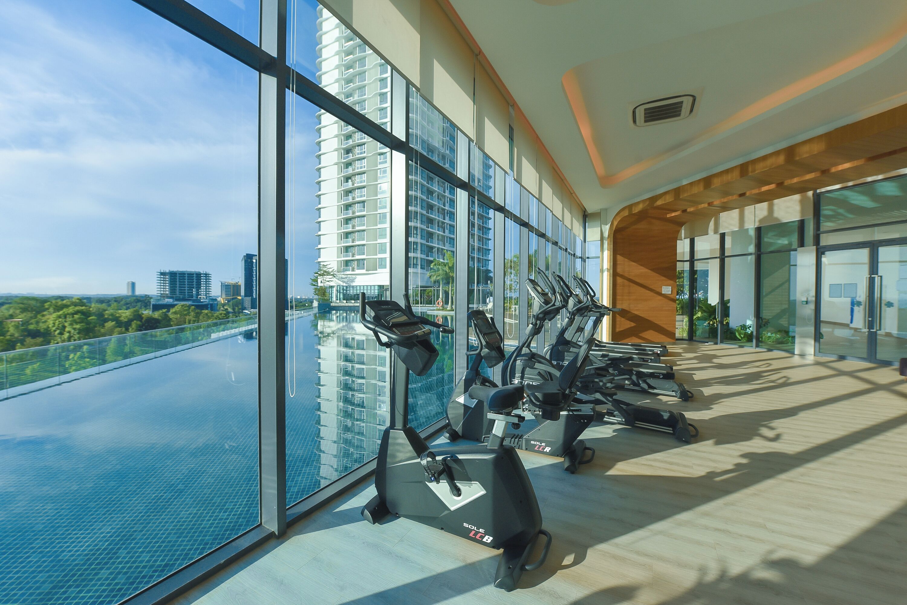 A gym with exercise bikes and a view of a cityscape through large windows.