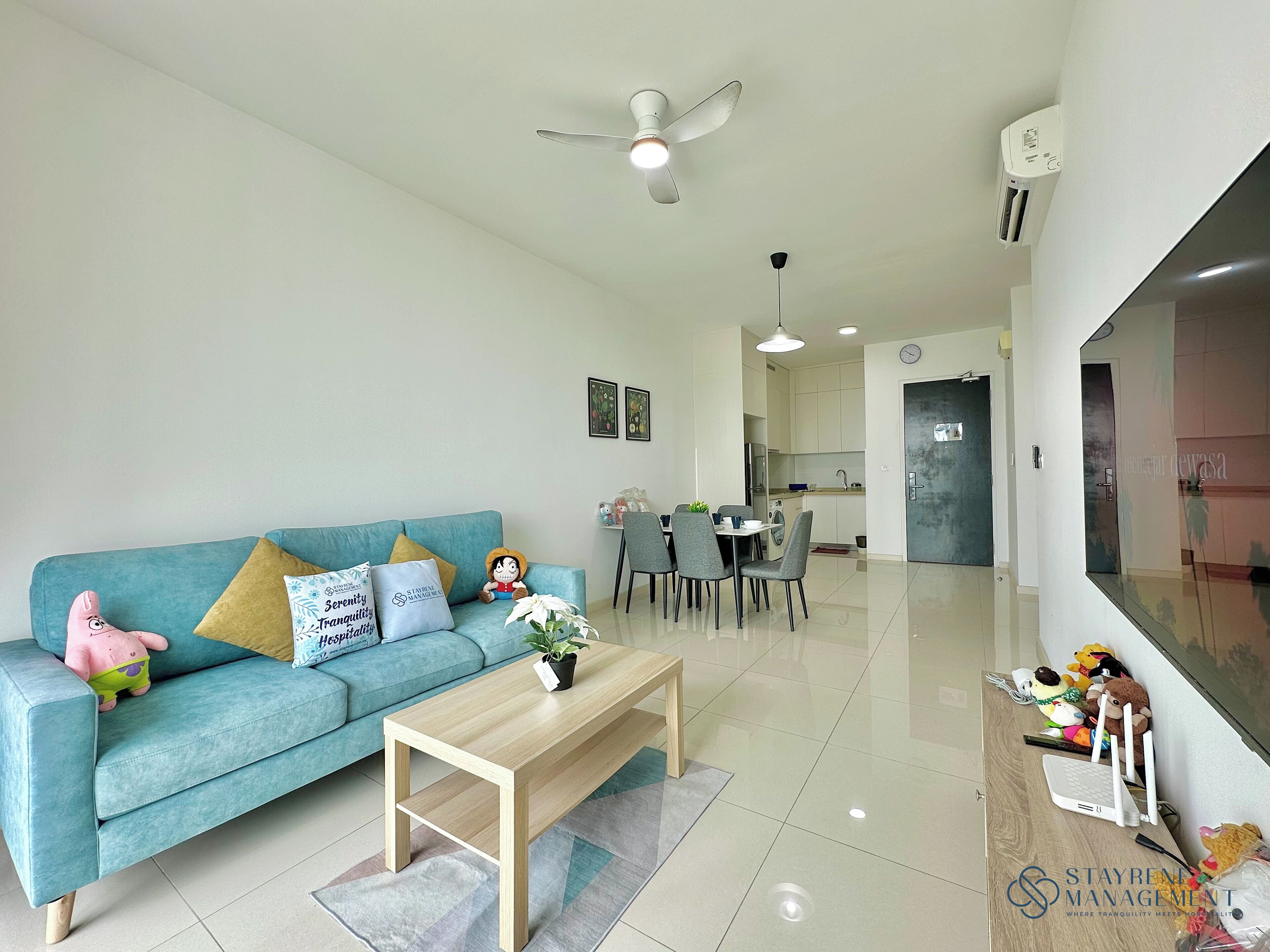 A modern living room with a teal sofa, a wooden coffee table, and a dining area with chairs.