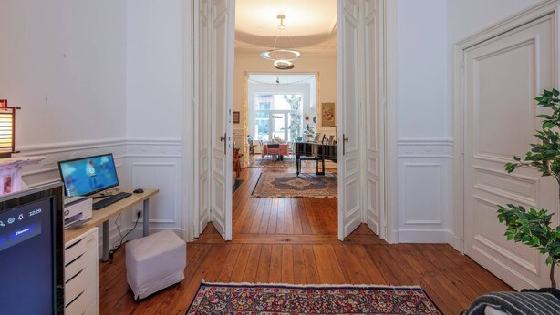 Un couloir avec un bureau, un ordinateur et une plante.
