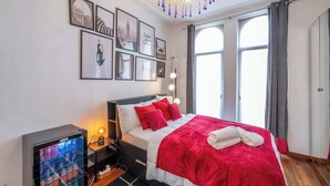 Une chambre d’hôtel équipée d’un lit, d’un minibar, d’une télévision et d’une grande fenêtre avec des rideaux.