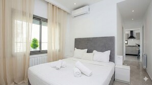 A modern hotel room with a large bed, white linens, a grey headboard, and an air conditioning unit on the wall. - Cozy stay with balcony view in La Marsa (Marsa)
