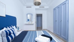 A hotel room with a bed, a nightstand, a mirror, and a wardrobe. - Le Petit Zéphyr – House near the beach (La Marsa)
