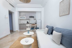 Een moderne woonkamer met een bank, een bijzettafeltje en een keuken op de achtergrond.