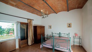A room with a bed, a window, a wooden wardrobe, and a chandelier. - Farmhouse Greppo all'Olivo :to spend your vacation with your family! (Donoratico)