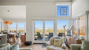 En rummelig stue med en stor skydedør til en terrasse med udsigt over stranden.