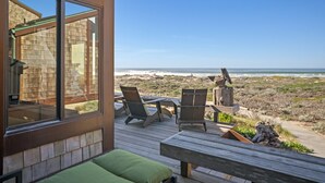 En træterrasse med stole og en bænk med udsigt over stranden.