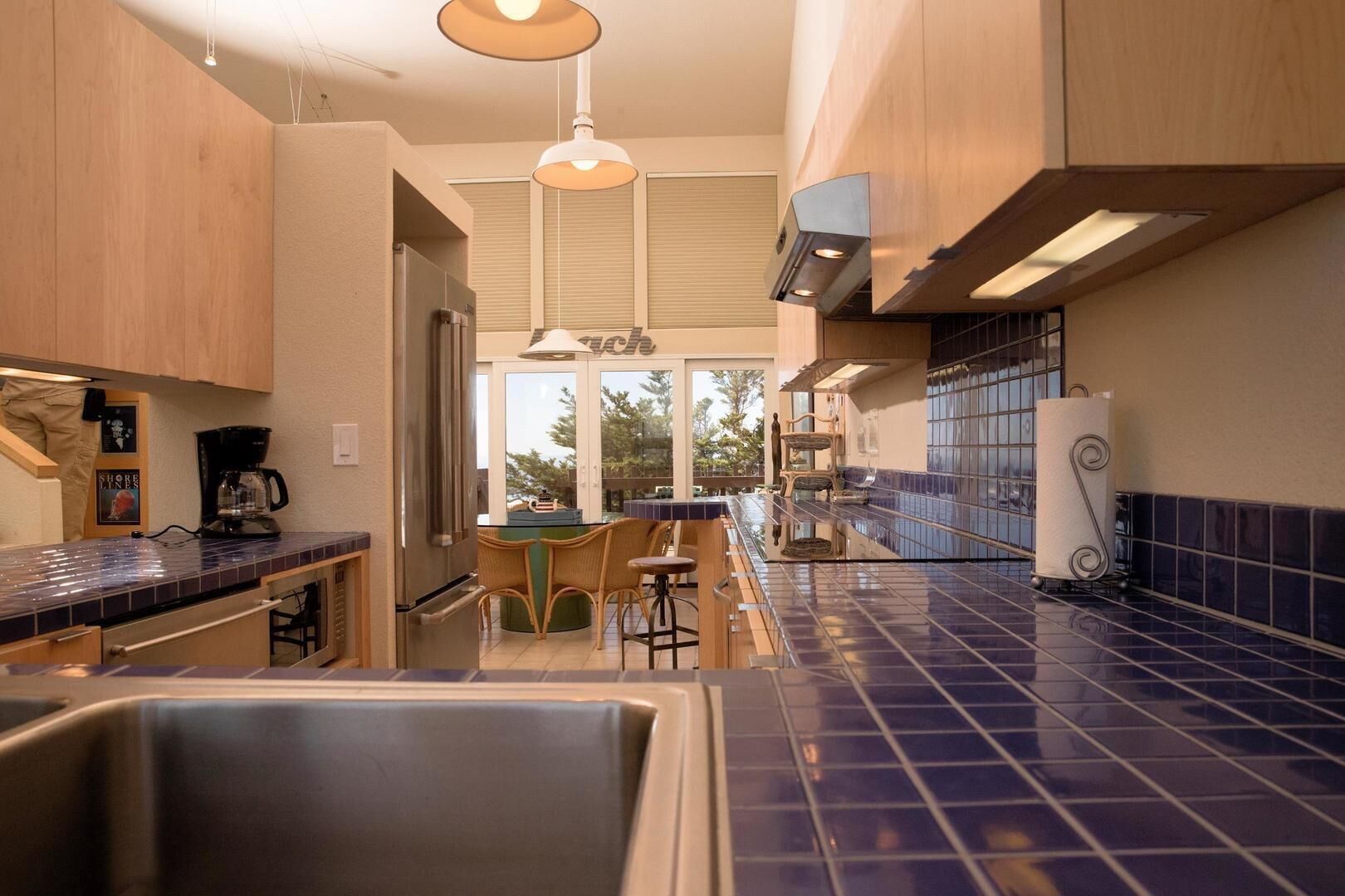 A modern kitchen with a central island, wooden cabinets, and a blue-tiled backsplash.