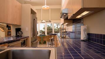 A modern kitchen with a central island, wooden cabinets, and a blue-tiled backsplash.